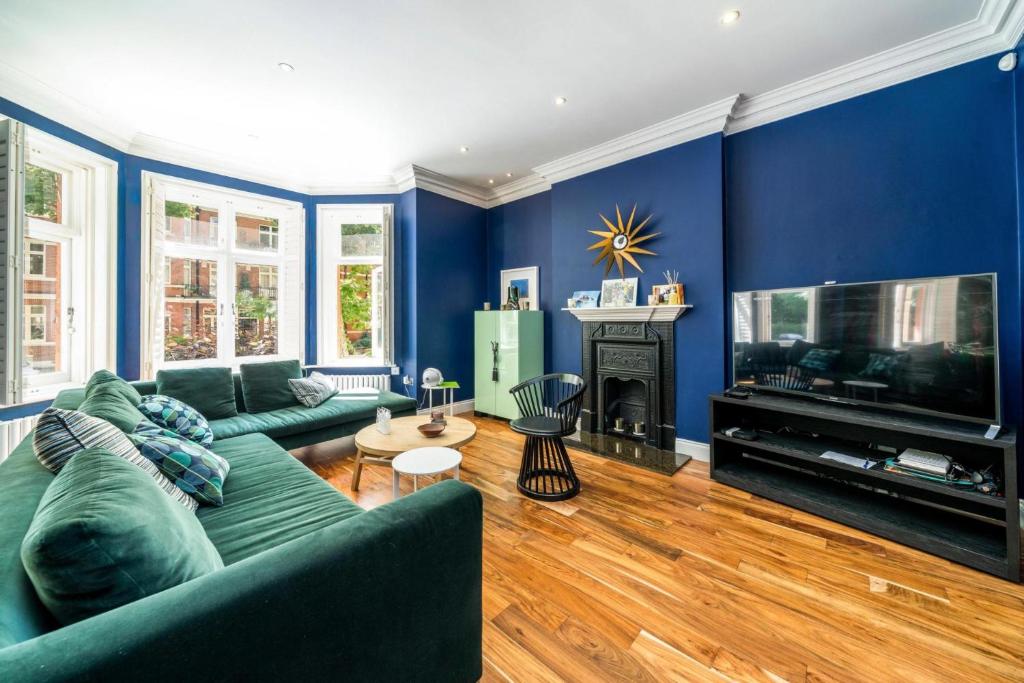 a living room with blue walls and a green couch at NEW Elegant 2BD Flat Maida Vale Central London in London