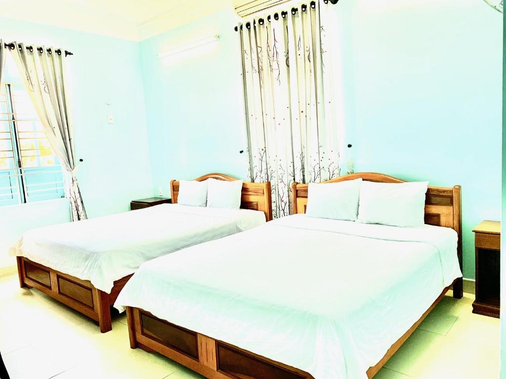 Habitación con 2 camas individuales y paredes blancas. en Areca Homestay en Hoi An
