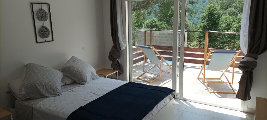 sypialnia z łóżkiem i balkonem z krzesłami w obiekcie Maison 38m2 15min de Corte 30min de Bastia w mieście Bigorno