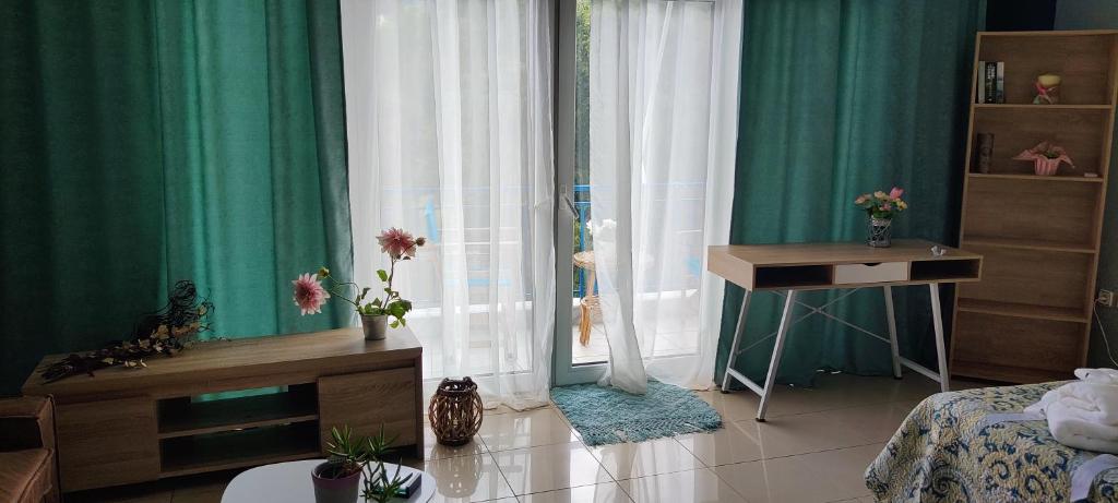 um quarto com cortinas verdes, uma cama e uma secretária em Hospitable appartment in the central park, Xanthi em Xanthi