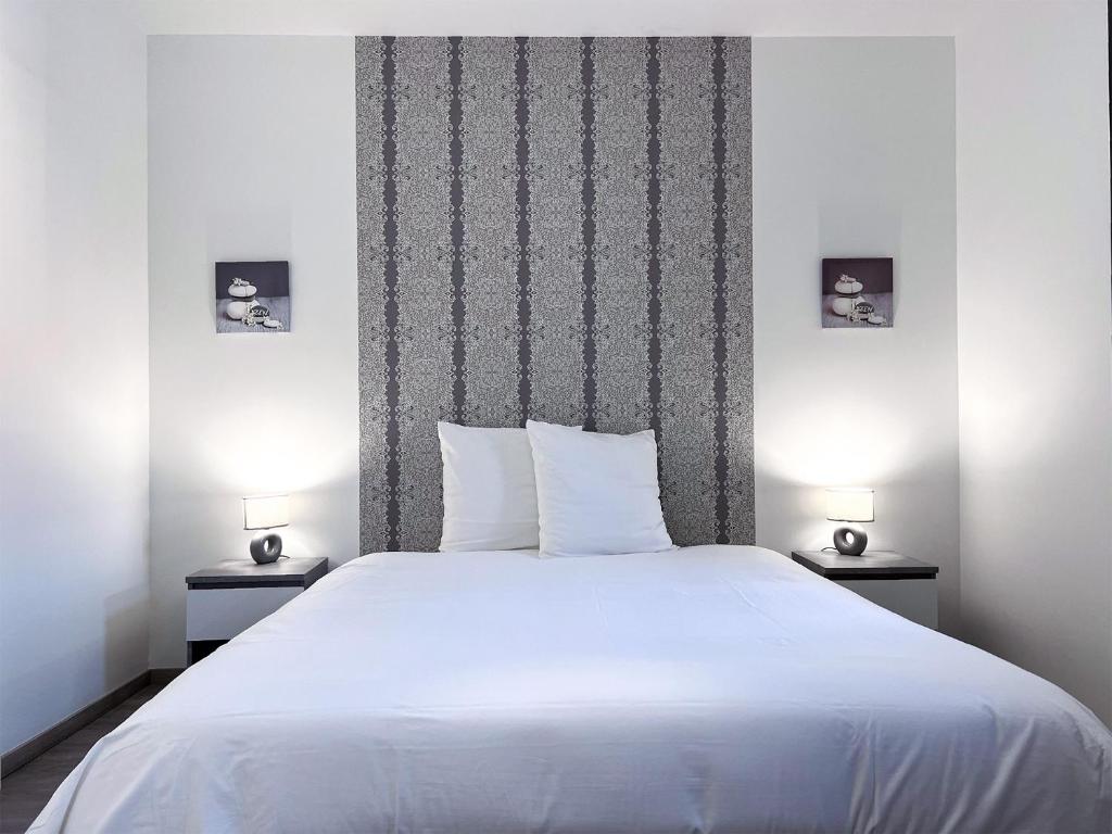 a bedroom with a large white bed with two lamps at Le frère Charmes in Aurillac