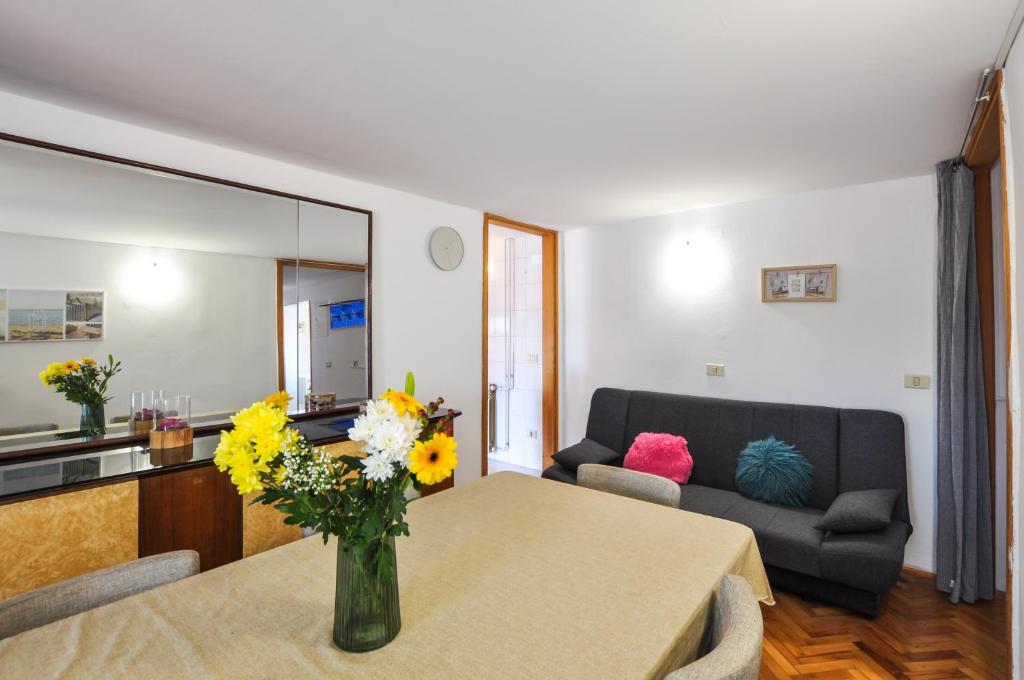 ein Wohnzimmer mit einem Tisch und einer Blumenvase in der Unterkunft Apartment KATARINA Koper - old historic centre with free parking in Koper