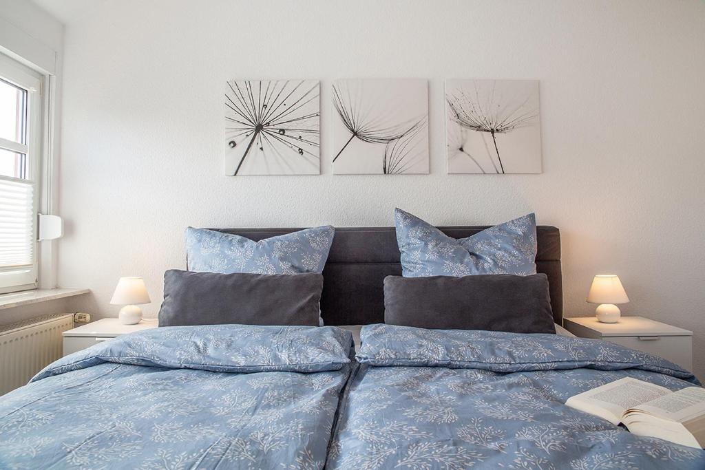 ein Schlafzimmer mit einem blauen Bett mit drei Gemälden an der Wand in der Unterkunft 50137 "Deichkajüte 6" in Carolinensiel
