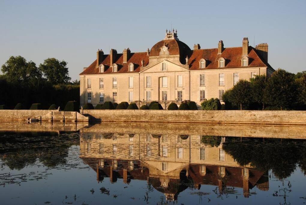 a large building with its reflection in the water at Au Pont Vert in Fontaine-Française