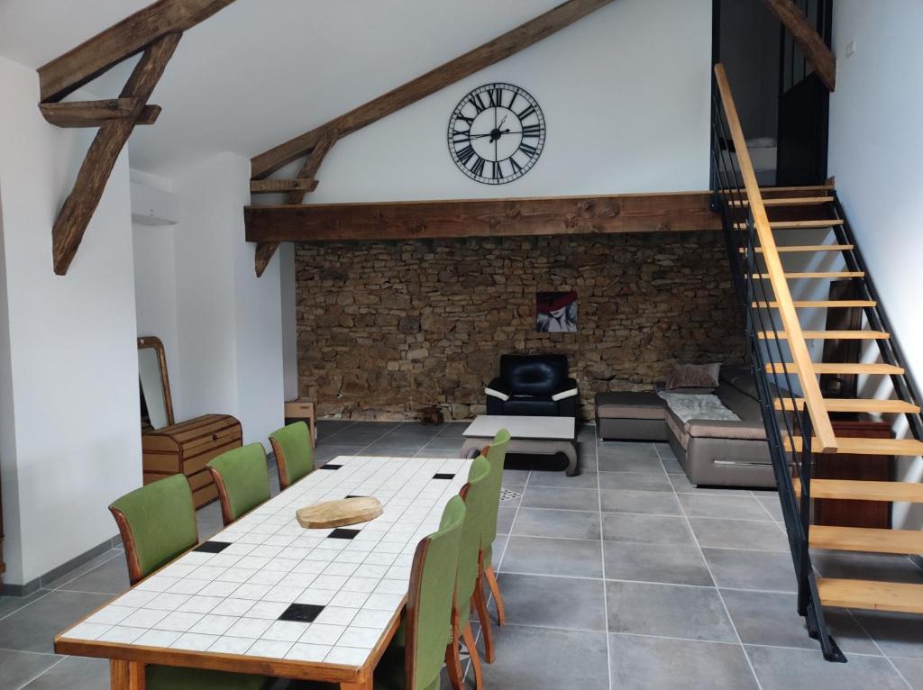 a living room with a table and chairs and a clock at La tourterelle in Cayriech