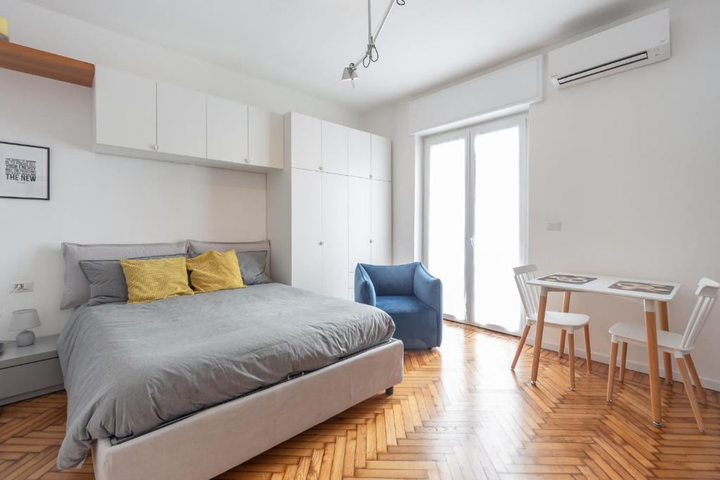 una camera con letto e tavolo con sedia blu di Appartamento Ripa Milano a Milano