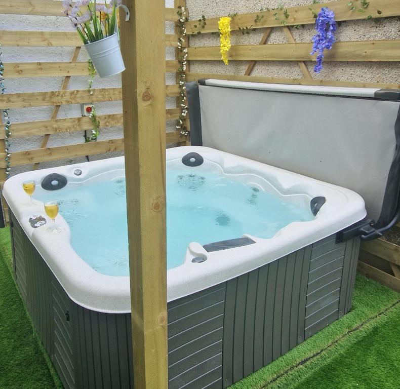 a jacuzzi tub in a yard with a fence at Coorie Braw Cottage in Kirn