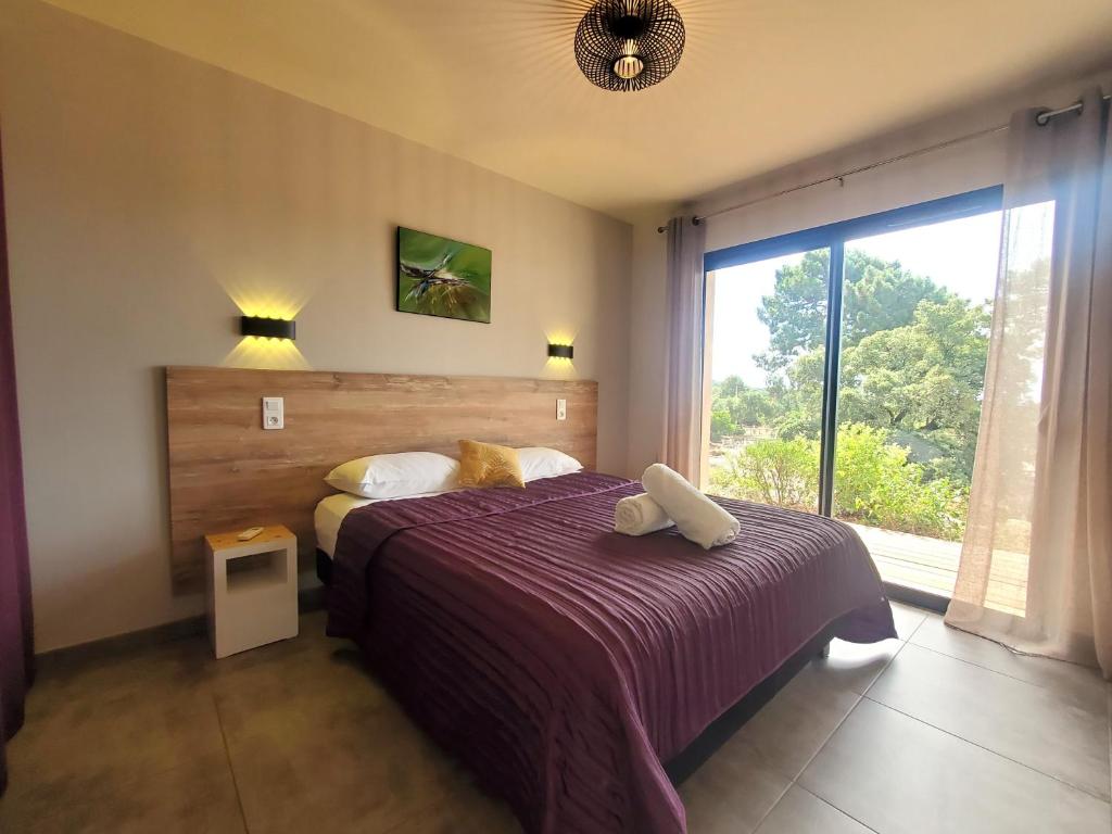 een slaapkamer met een bed en een groot raam bij Villas Lantana in Porto-Vecchio