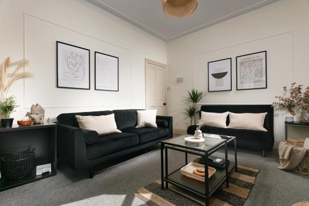 a living room with a black couch and a table at Central Plymouth Home - SLEEPS up to 10 - Free On Street Parking - Pets welcome - By Luxe Living in Plymouth