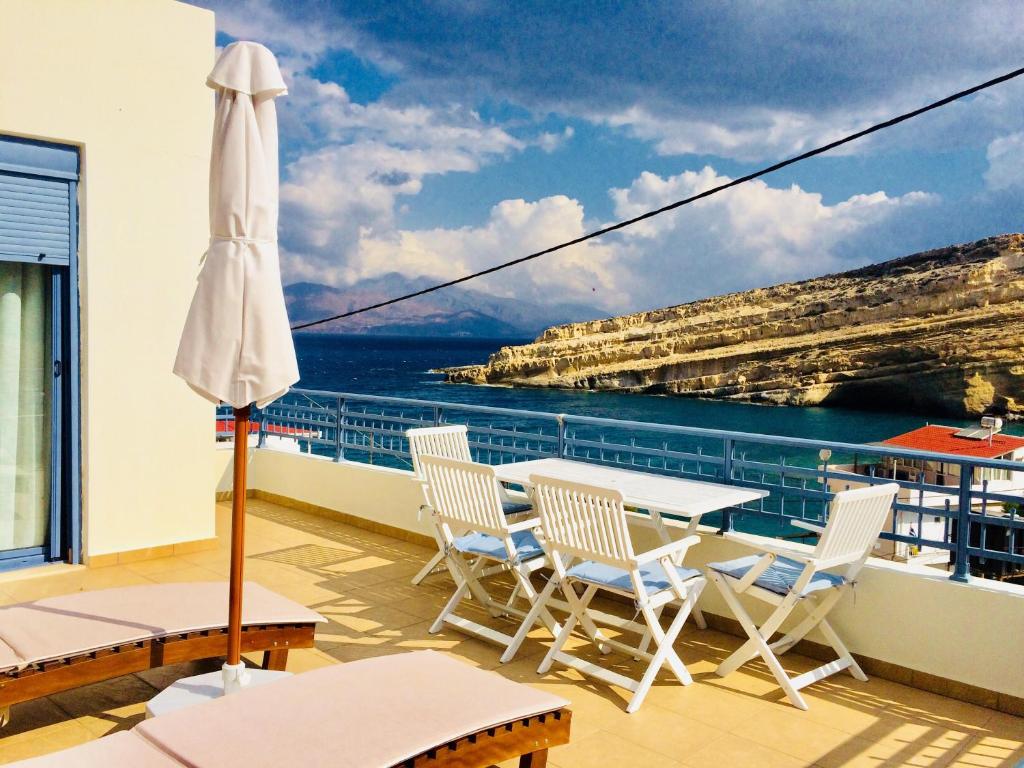 balkon ze stołem, krzesłami i parasolem w obiekcie Villa Red Beach - Matala Love w mieście Matala