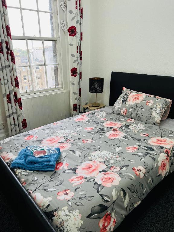 a bedroom with a bed with a floral comforter at HISTORIC ROYAL MILE FLAT , 5min FROM WAVERLY RAILWAY STATION in Edinburgh