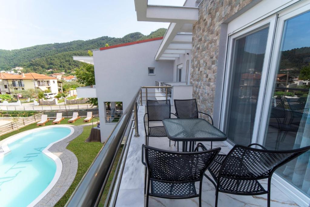 balcón con sillas y piscina en Amalthia en Skala Potamias