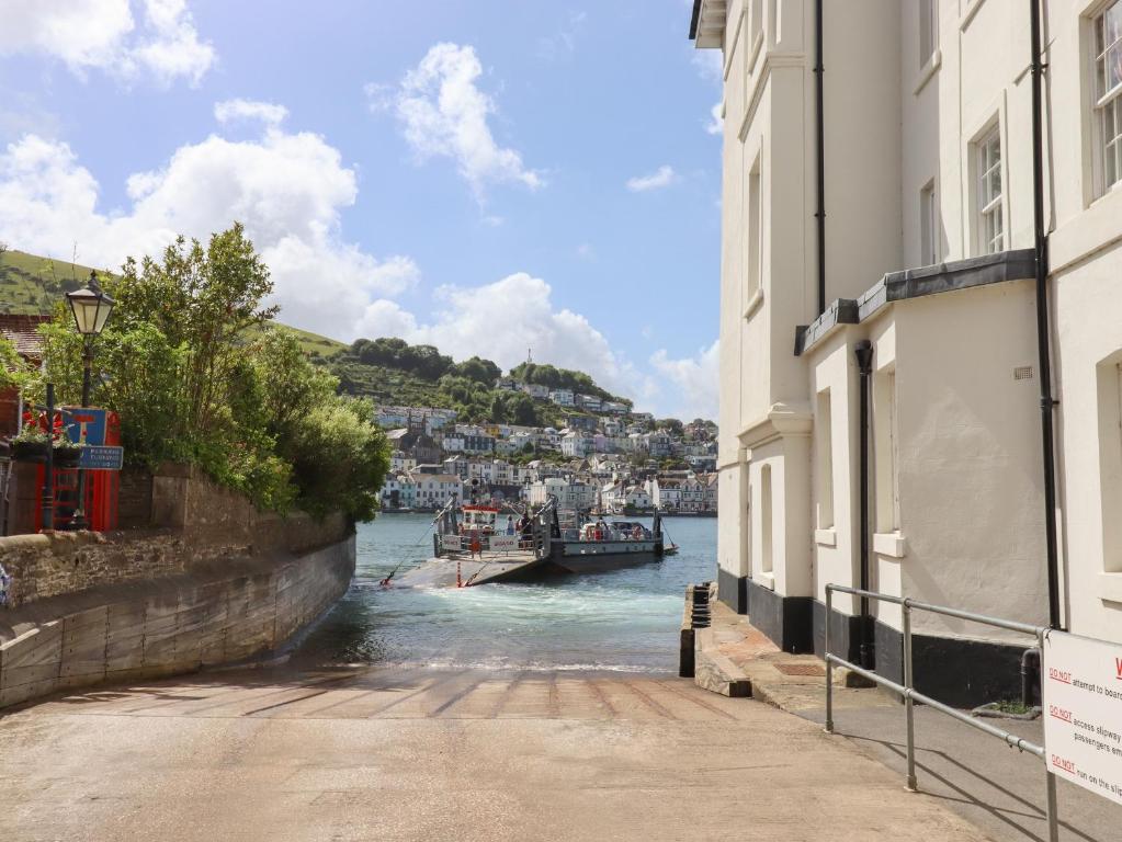 a river between two buildings with a boat in the water at Ferryside in Dartmouth