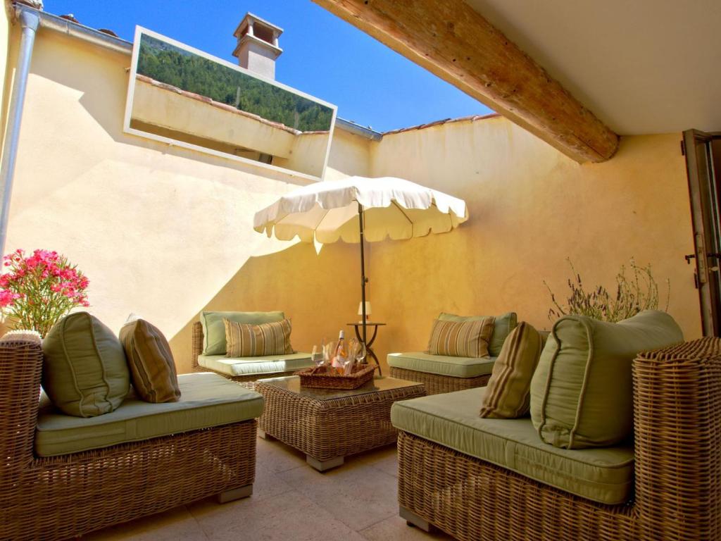 a patio with wicker chairs and an umbrella at Luxurious Provencal Village House, Walk to Village Pool in Rustrel