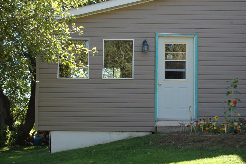 uma casa castanha com uma porta azul e janelas em North Rustico Bed and Breakfast em North Rustico