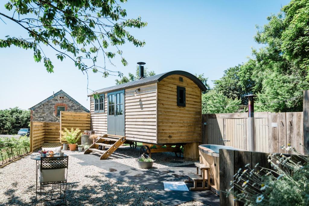 Boutique Cornish Shepherd's Hut with Hot Tub في لاونسستون: كابينة خشبية في ساحة مع سور