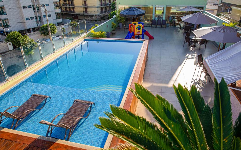 - une vue sur la piscine avec des chaises et une aire de jeux dans l'établissement Pousada Valle Verde, à Cabo Frio