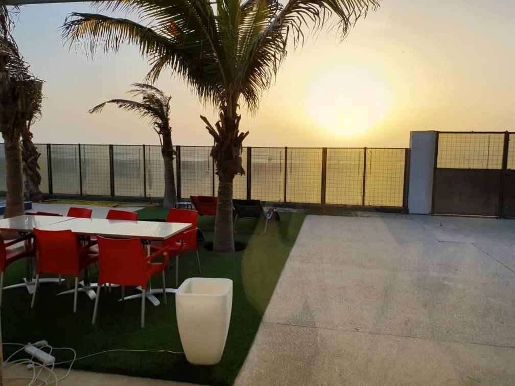 Guet Dar的住宿－TérangaLux Villa A Vue Mer avec Piscine Saint Louis Sénégal，一个带桌椅和棕榈树的庭院