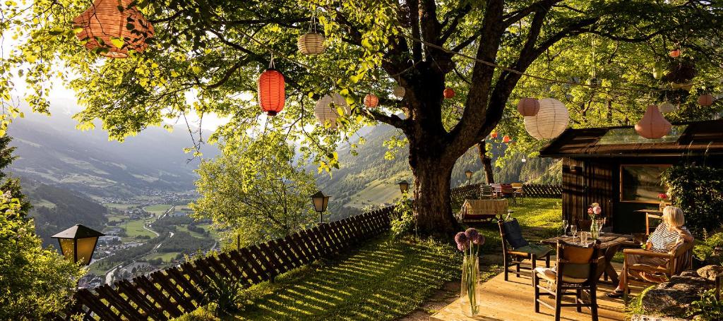 een huis met een tafel en stoelen onder een boom bij Waldhaus Rudolfshöhe in Bad Gastein