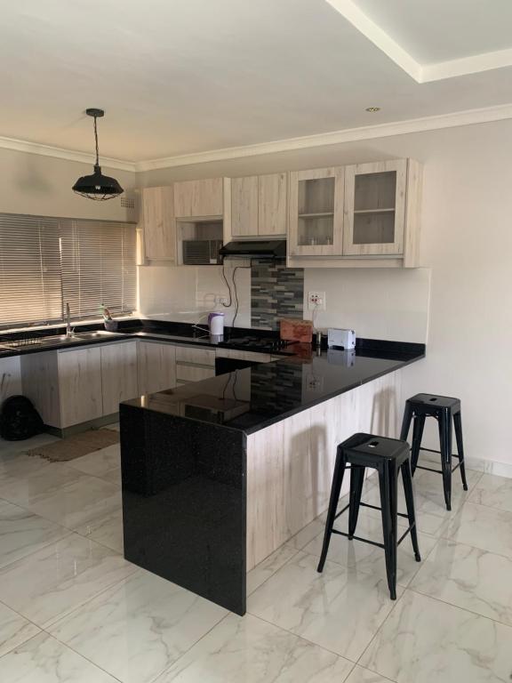 a kitchen with a black counter and two stools at Greendale Apartments in Lusaka