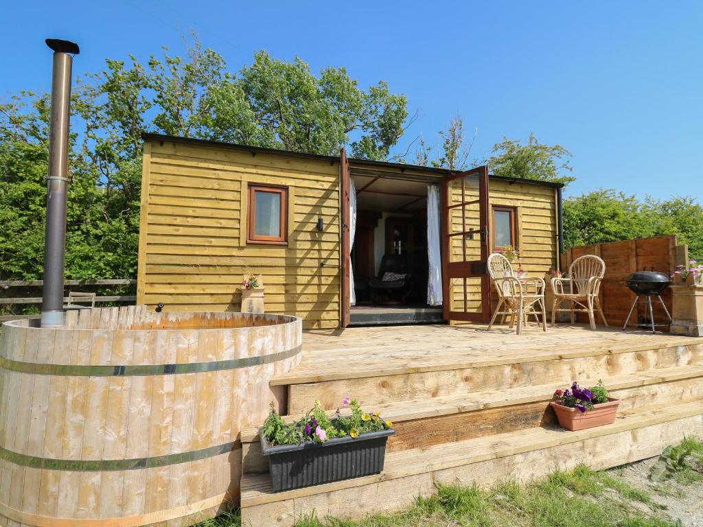 a tiny house with a wooden deck and a patio at Hawthorn Hut in Llanidloes