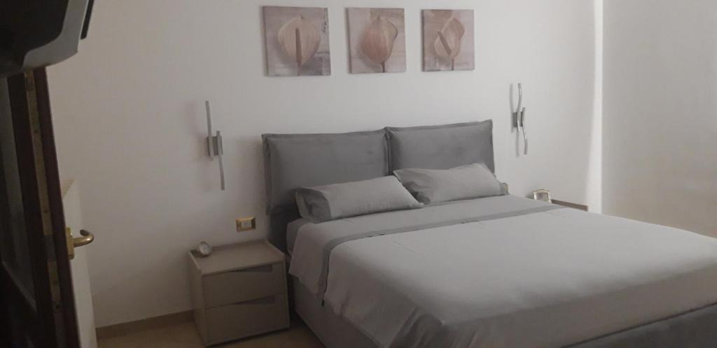 ein Schlafzimmer mit einem weißen Bett und zwei Bildern an der Wand in der Unterkunft Gioia del salento in Lecce