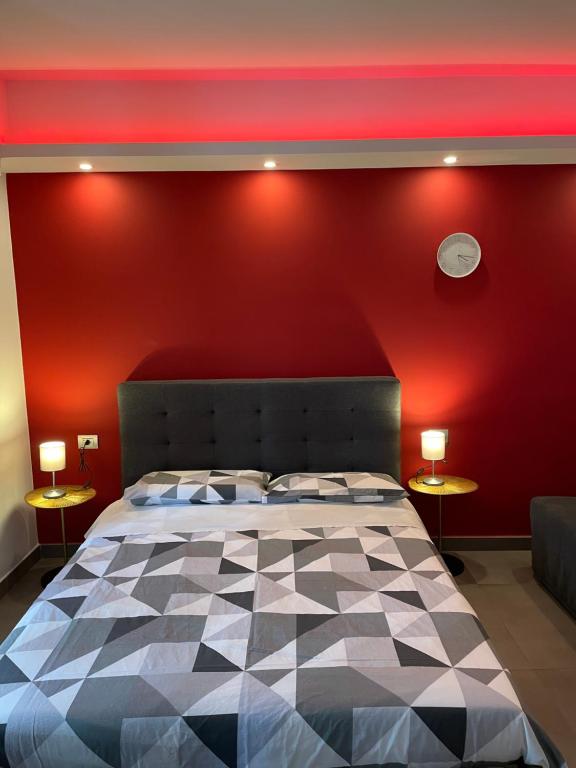 1 dormitorio con una pared roja, 1 cama y 2 lámparas en Stella Rooms, en Catania