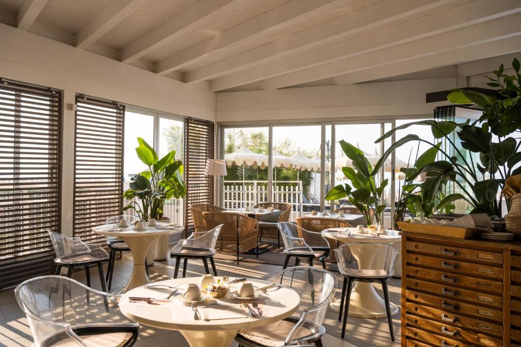 un restaurant avec des tables, des chaises et des fenêtres dans l'établissement Hotel Delle Nazioni, à Lido di Jesolo