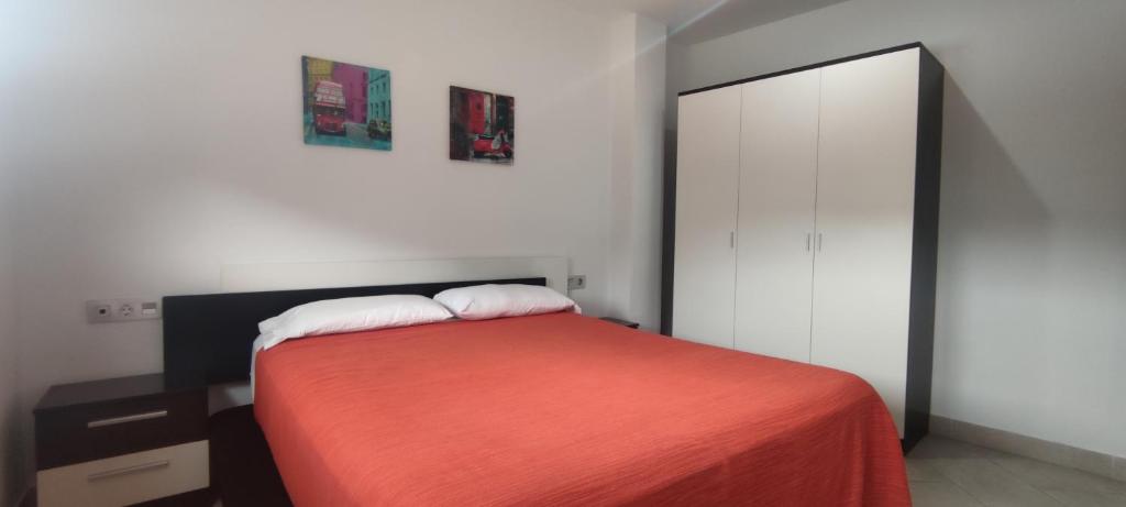 a bedroom with a bed with a red blanket and a mirror at Apartamentos Cala Azul La Móra in Tarragona