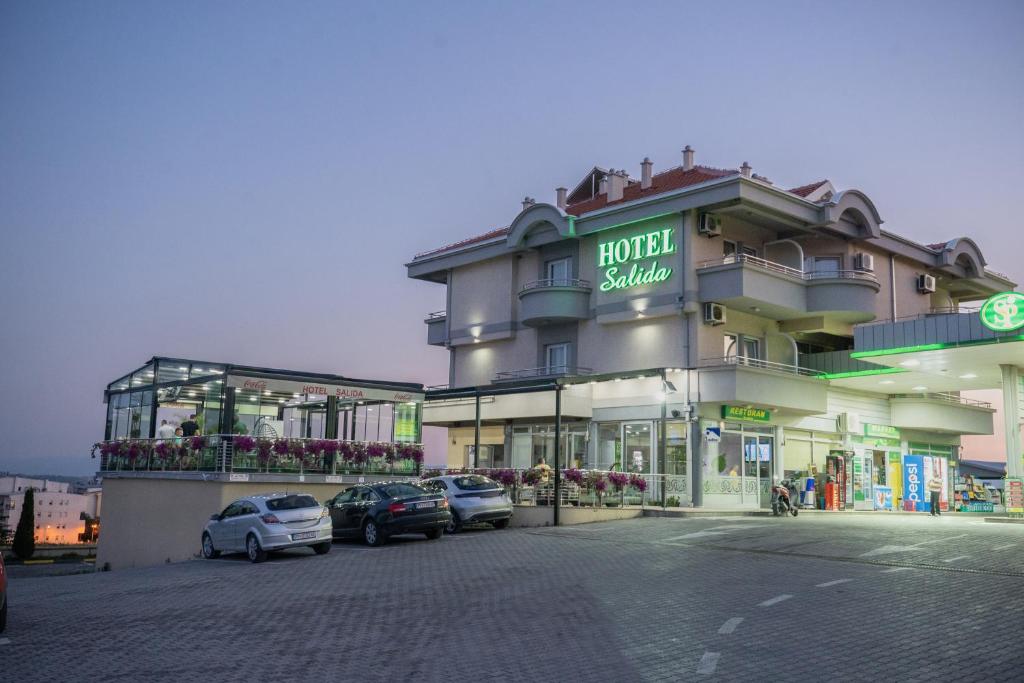 un grand bâtiment avec des voitures garées devant lui dans l'établissement Hotel Salida, à Prilep