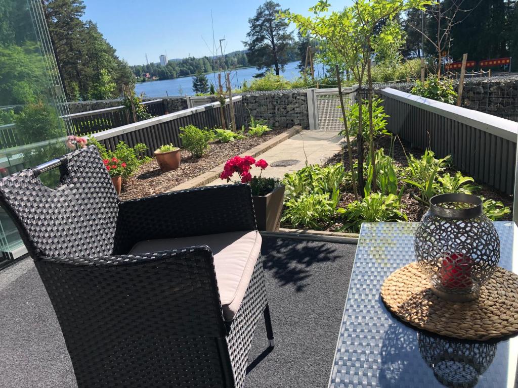 eine Terrasse mit 2 Stühlen und einem Tisch mit einer Vase in der Unterkunft Lake view Helmi in Jyväskylä