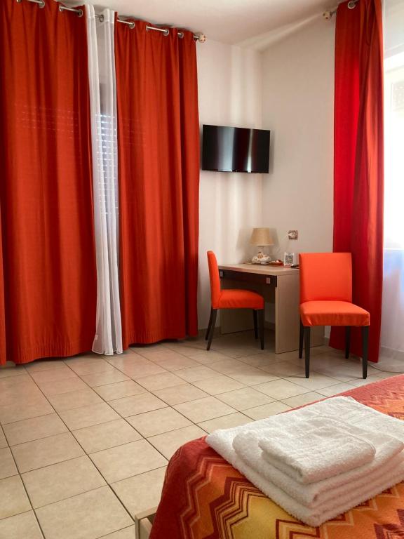 una camera da letto con tende rosse e una scrivania con sedie di Solìa Bed & Breakfast a Scalea