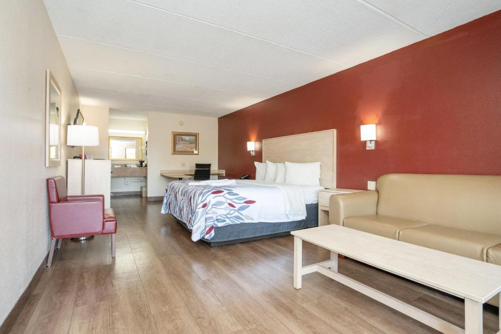 a hotel room with a bed and a couch at Red Roof Inn & Suites Pigeon Forge Parkway in Pigeon Forge