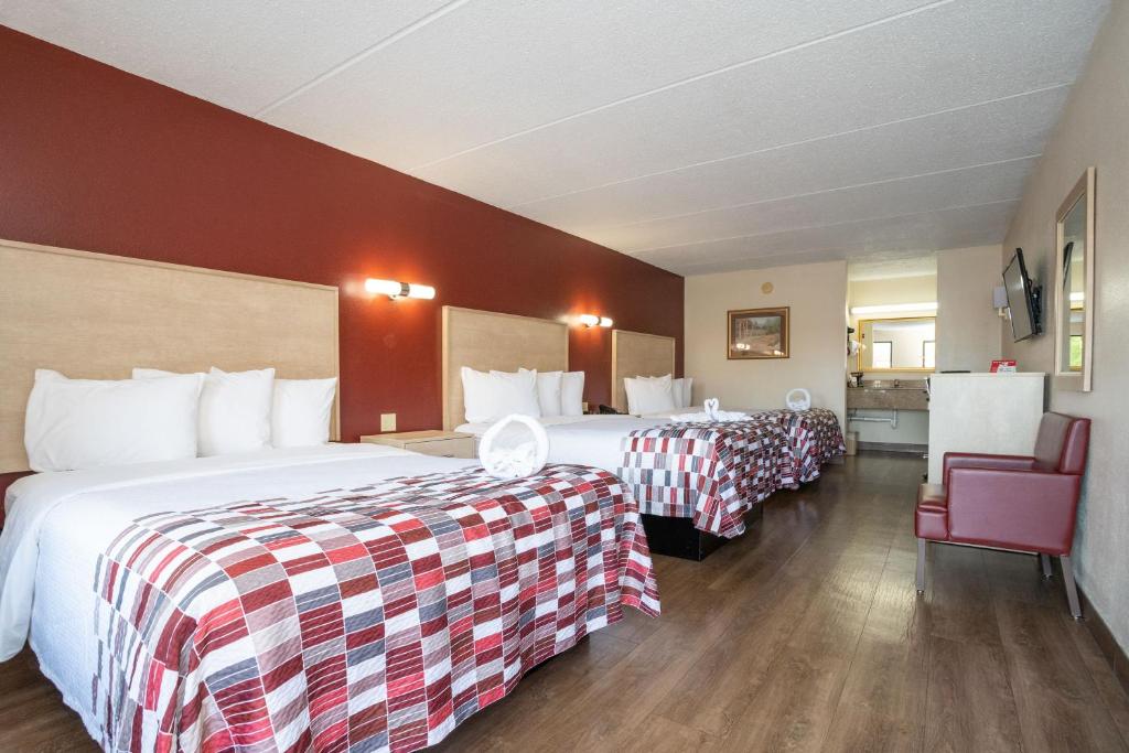 a hotel room with two beds and a chair at Red Roof Inn & Suites Pigeon Forge Parkway in Pigeon Forge