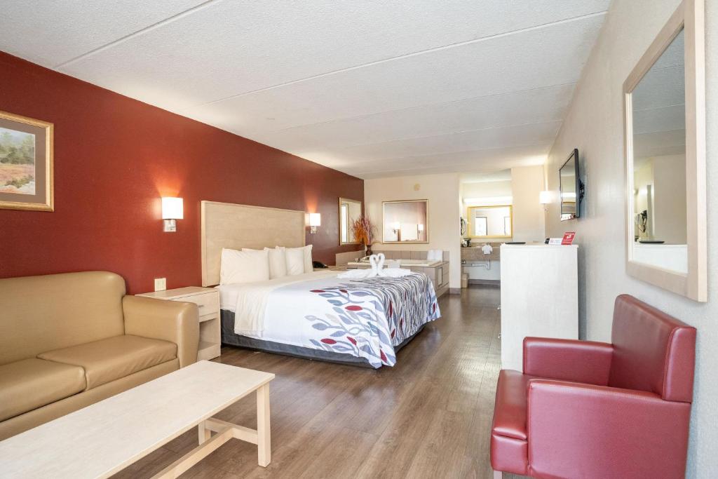 a hotel room with a bed and a couch at Red Roof Inn & Suites Pigeon Forge Parkway in Pigeon Forge