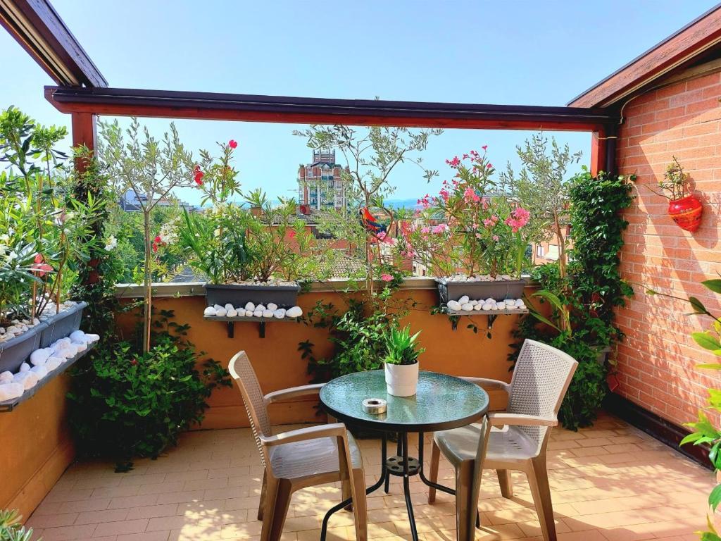 un patio con mesa, sillas y plantas en ATTICO IN FIERA apartment, en Bolonia
