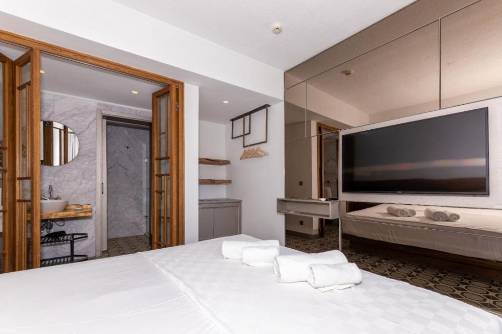 a bedroom with a large white bed and a large tv at Mükellef Gümüşlük in Bodrum City