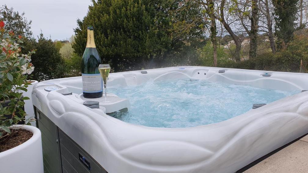 a hot tub with a bottle of wine in it at Villa la Dunette & spa in Vaux-sur-Mer