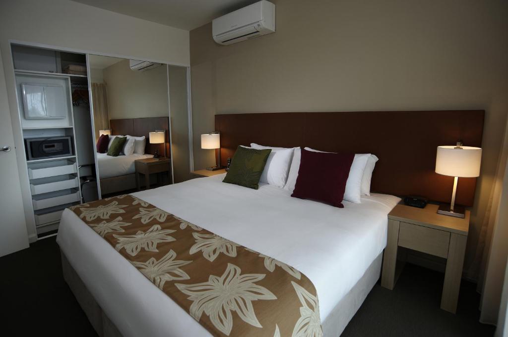 ein Hotelzimmer mit einem großen Bett und zwei Lampen in der Unterkunft Quest Palmerston - Darwin in Darwin