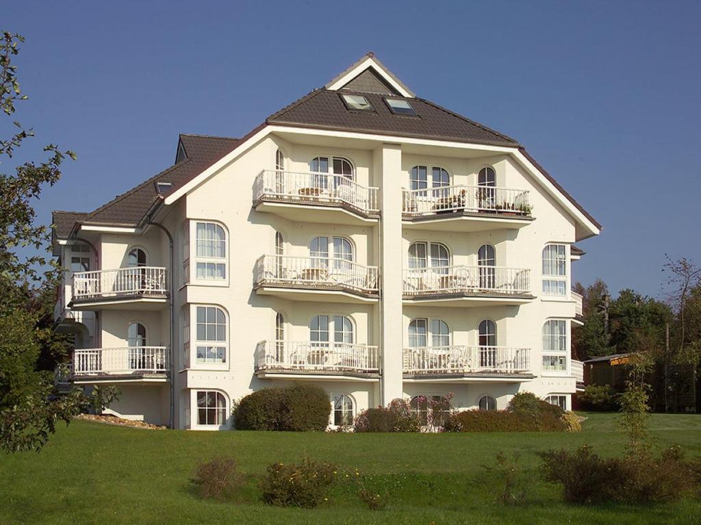 ein großes weißes Gebäude mit Balkonen auf einer Wiese in der Unterkunft Haus Südstrand, Scharbeutz-Sierksdorf in Sierksdorf