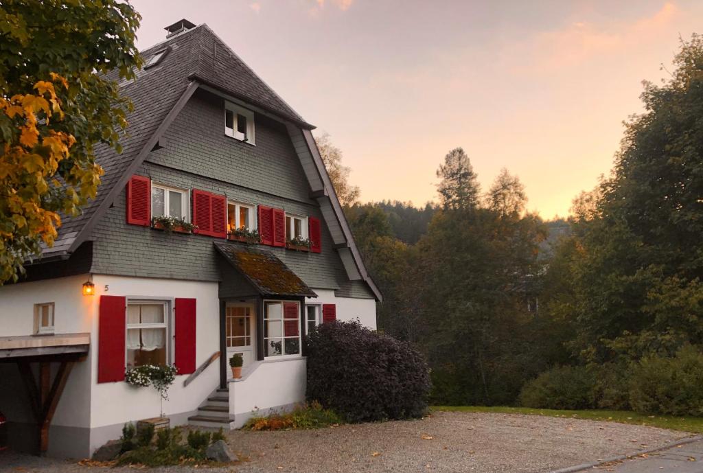 uma casa branca e vermelha com persianas vermelhas em Haus Nagel em Hinterzarten