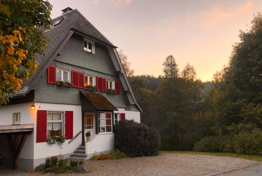 una casa bianca e rossa con persiane rosse di Haus Nagel a Hinterzarten