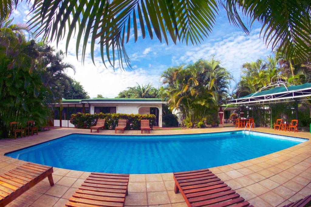 a large swimming pool with chairs and a house at Hotel La Rosa de America in Alajuela