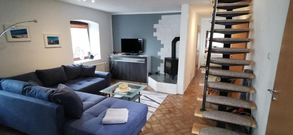 a living room with a blue couch and a spiral staircase at Gemütliches Ferienhaus An der Schilde in Renzow