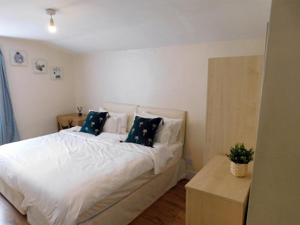 - une chambre avec un grand lit blanc et des oreillers bleus dans l'établissement Entire 4 bedroom Terrace house in London, à Londres