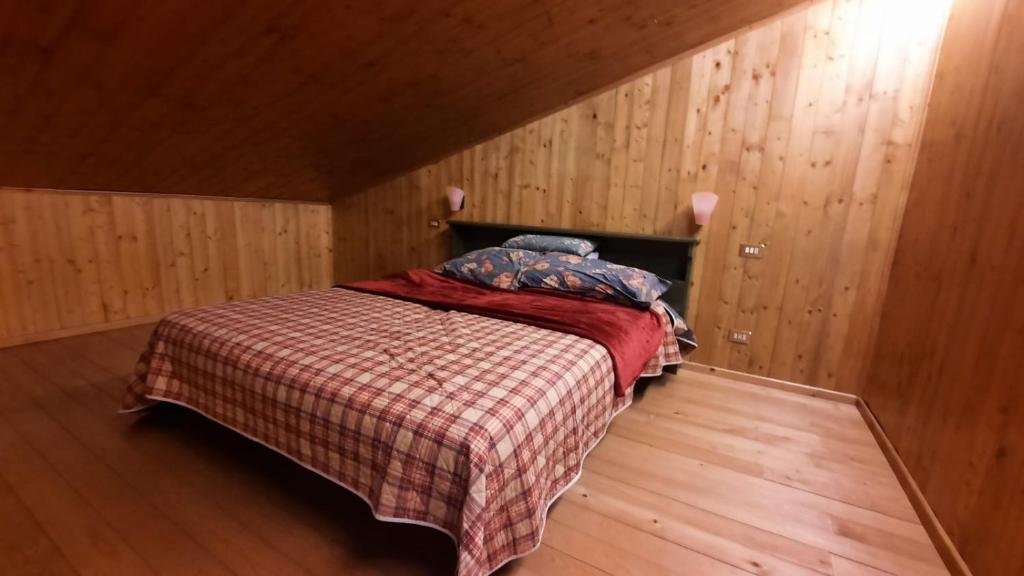 1 dormitorio con 1 cama con manta a cuadros en Cozy family apartment for rest and fun, en Sella Nevea