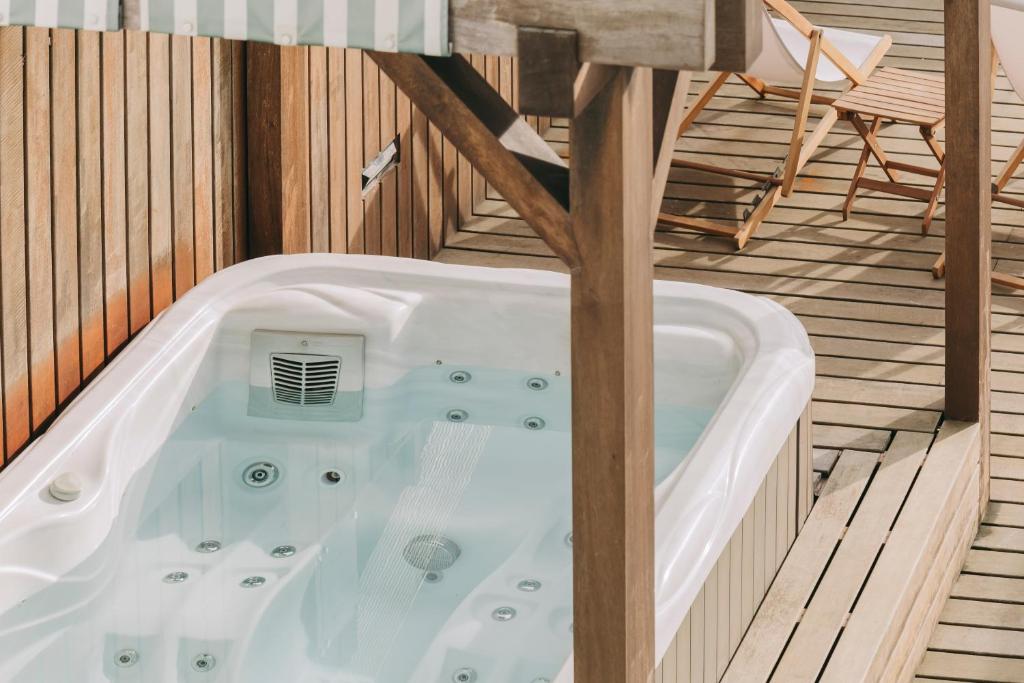 a jacuzzi tub on a deck with a chair at Coast Flats by Azores Villas in Ponta Delgada