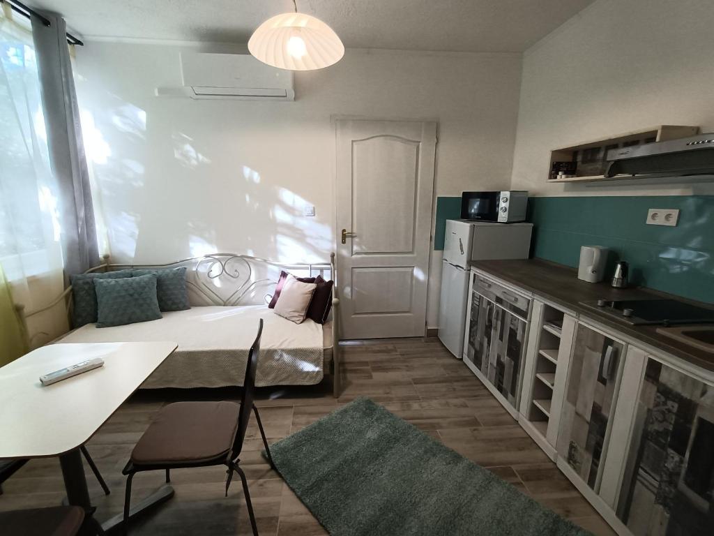 a small room with a bed and a table and a kitchen at Tölgyfa Vendégház in Balatonszepezd