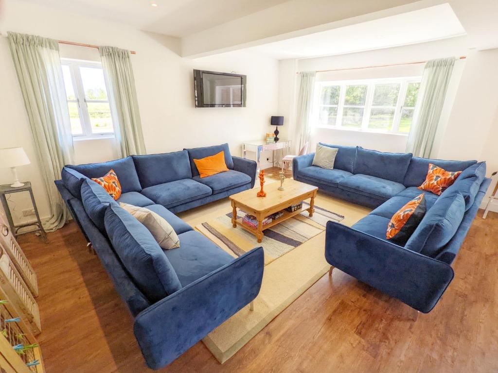 a living room with blue couches and a table at Priory Coach House - Church Norton in Selsey