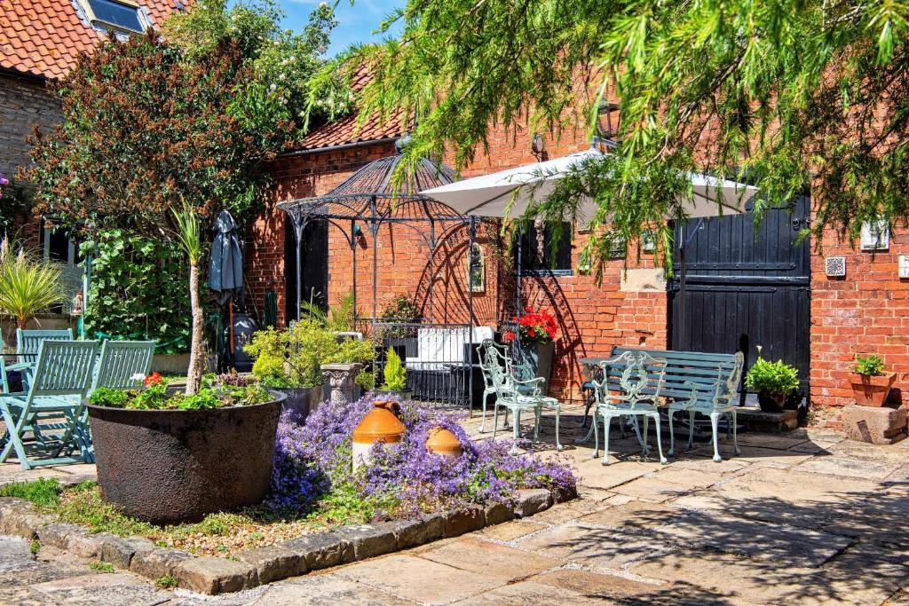 Finest Retreats - The Hayloft at Greystones في Swinderby: حديقة بها زهور أرجوانية وطاولة وكراسي